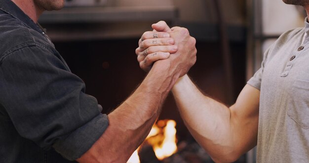 Foto reunión de apretón de manos y asociación con hombres en un taller juntos para un trato o acuerdo trabajo en equipo bienvenido y saludo con gente de la industria masculina dándose la mano en una fábrica para dar las gracias