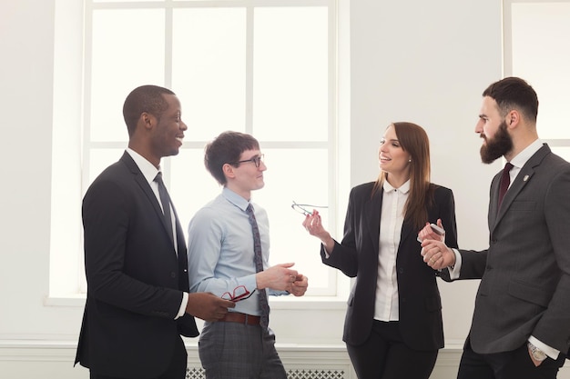 Reunión corporativa en la oficina, gente de negocios conversando, de pie junto a la ventana. Trabajo en equipo, concepto de lluvia de ideas, espacio de copia