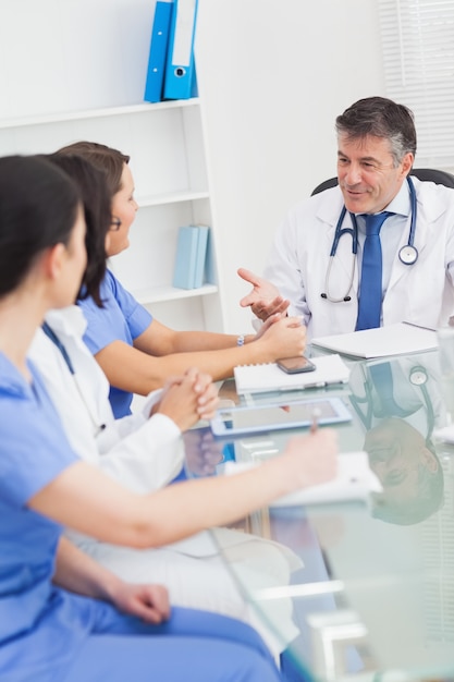 Reunión entre un doctor y tres enfermeras que sonríen