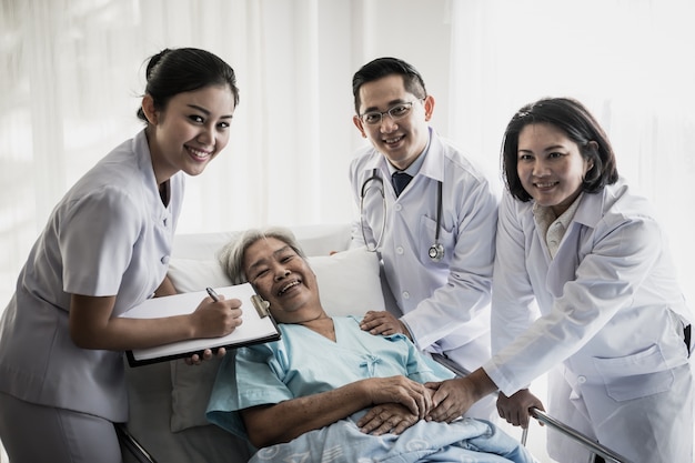 Reunión del equipo médico con el paciente mayor en la habitación del hospital