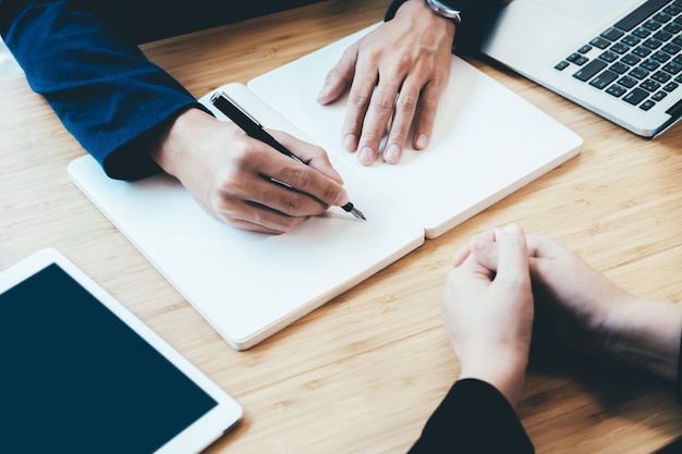 Reunión y escritura del hombre de negocios en cuaderno.