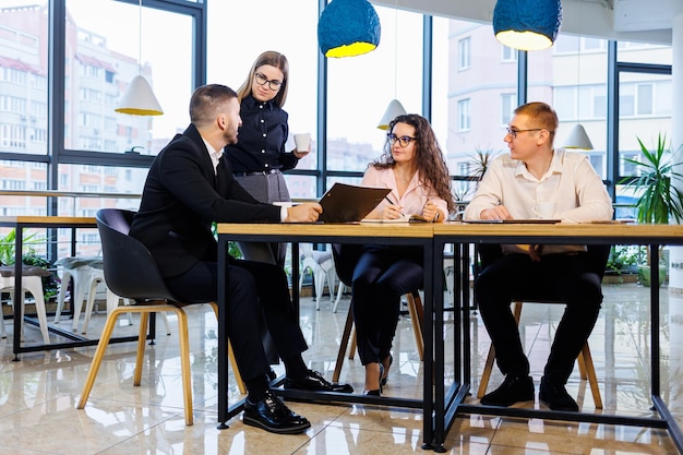 Reunión exitosa de gente de negocios, discutiendo nuevas ideas de negocios, usando diagramas, sentados juntos. Fondo de oficina moderna. Reunión de socios comerciales en la conferencia sobre desarrollo empresarial