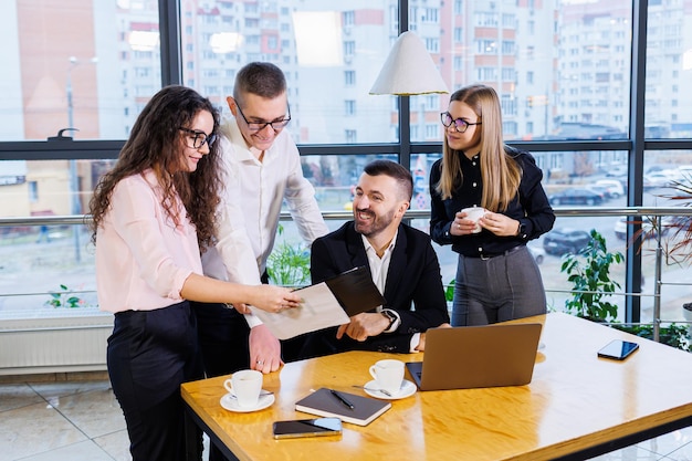 Reunión exitosa de gente de negocios, discutiendo nuevas ideas de negocios, usando diagramas, sentados juntos. Fondo de oficina moderna. Reunión de socios comerciales en la conferencia sobre desarrollo empresarial