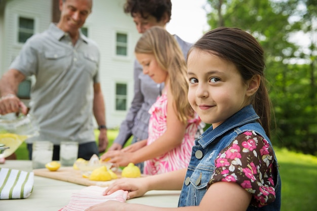 Foto una reunión familiar de verano en una granja una niña rebanando y exprimiendo limones para hacer limonada