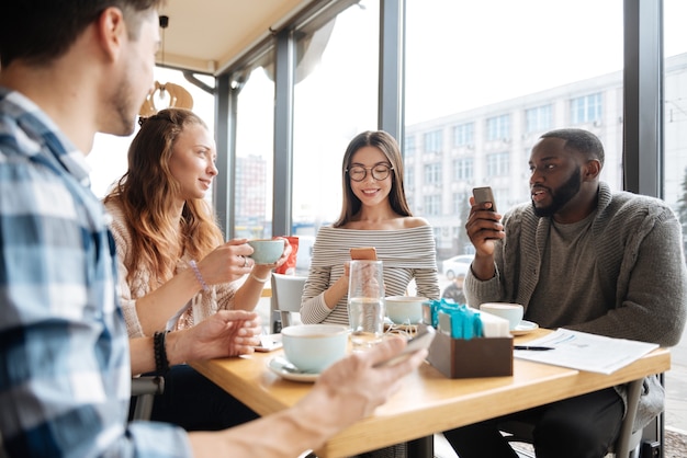 Reunión de fin de semana. Retratos de jóvenes internacionales que pasan su tiempo común juntos en la cafetería manteniendo una agradable conversación.