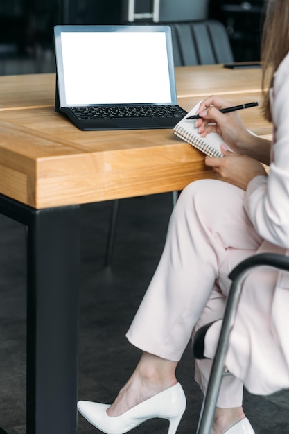 Reunión en línea computadora maqueta tecnología digital mujer elegante irreconocible sentado escritorio con