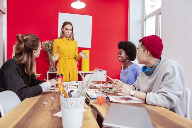 Reunión matutina. Diseñadores de moda con estilo que tienen una reunión matutina tradicional discutiendo un nuevo proyecto