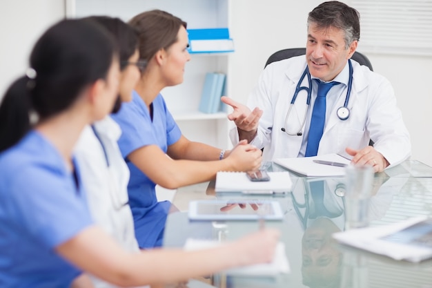 Reunión entre un médico y tres enfermeras y un médico sonriendo