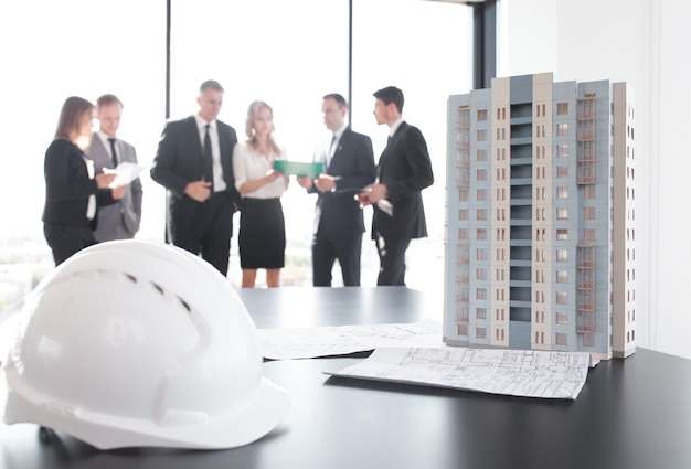 Reunión de negocios de arquitectos e inversores mirando el modelo de casa de edificio residencial moderno de varios pisos en la mesa