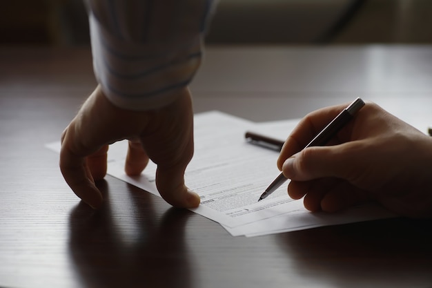 Reunión de negocios. Un hombre firma un contrato. Mano masculina con lápiz hace notas en la oficina.