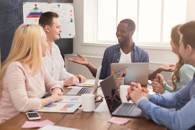 Reunión de negocios del joven equipo multiétnico. Discusión de la oficina del nuevo proyecto, jefe afroamericano comunicándose con socios en la oficina, espacio de copia