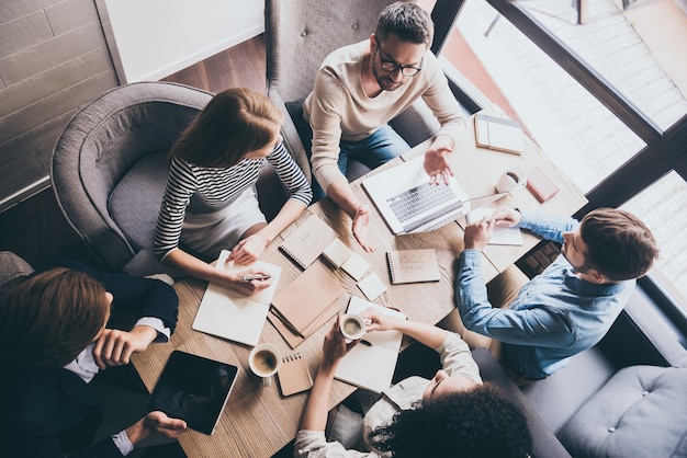 Foto reunión de negocios. vista superior de la lluvia de ideas del equipo de negocios mientras está sentado en la mesa de la oficina juntos