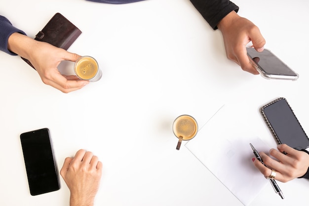 Reunión de trabajo en equipo en una mesa, con manos y cafés, vista superior