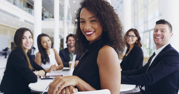 Estas reuniones siempre son informativas Captura recortada de una joven empresaria sonriendo en una oficina durante una reunión con sus colegas en el fondo