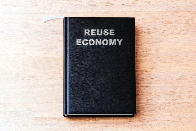 Reutilización del libro negro de negocios de economía en la mesa de madera de la oficina