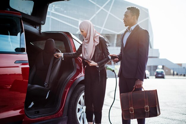 Revendedor feminino mostrando carro elétrico para cliente africano