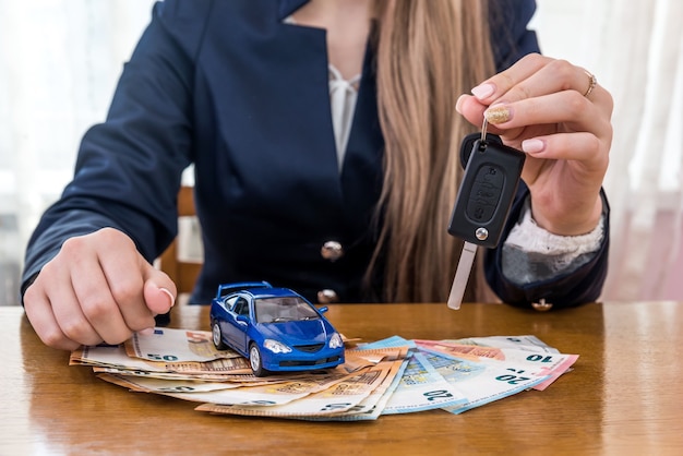 Foto revendedor segurando as chaves de um carro, carro de brinquedo e dinheiro em euros