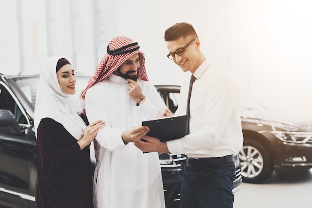 Revendedor vende carro árabe rico cliente lê contrato.