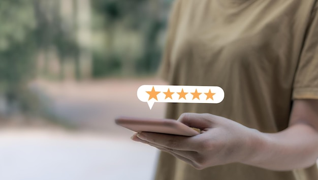 Revisão do cliente Mulher jovem com smartphone na mão com cinco estrelas para analisar e dar 5 estrelas