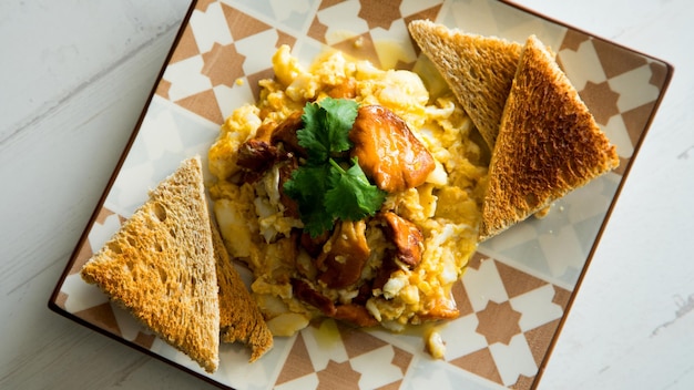 Revuelto de huevos y champiñones sobre pan tostado