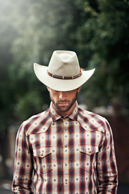 Los reyes tienen coronas, pero un vaquero solo tiene un sombrero Foto de un apuesto vaquero con camisa a cuadros y sombrero Stetson