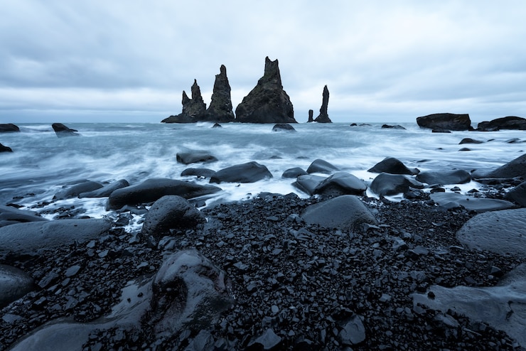 Foto reynisdrangar seastacks in der nähe von reynisfjara strand durch das küstendorf vik, island