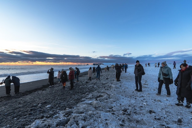 Reynisfjara schwarzer Sandstrand bei Sonnenuntergang mit Touristen, die rennen, weil sie von einer Welle erfasst werden