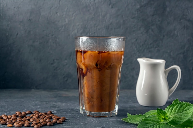 Rezept Eiskaffee mit Minze und Milch. Großes Glas mit schwarzem Kaffee. Kühles Sommergetränk auf dunklem Hintergrund in zurückhaltendem. Nahaufnahme, kopieren Sie Platz für Text.