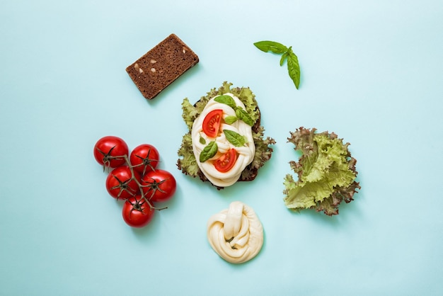 Rezept für einen gesunden Snack: Salatblätter, reife Tomaten, Cecil-Käse, Vollkornbrot. Leckeres und gesundes Sandwich, Ansicht von oben