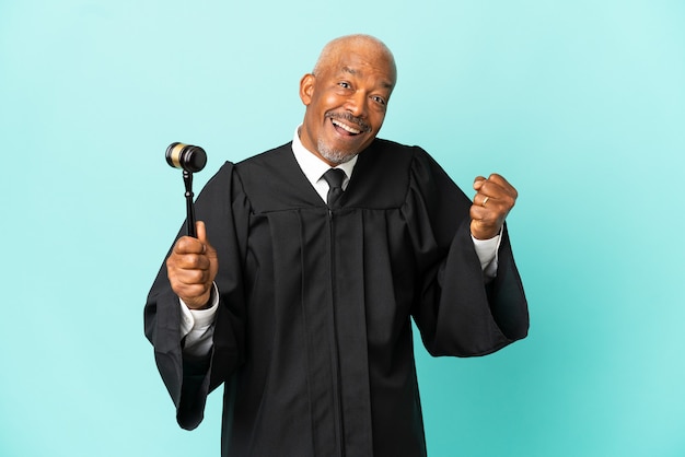Richter senior Mann isoliert auf blauem Hintergrund feiert einen Sieg in Siegerposition