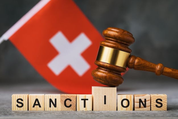 Richterhammer, Holzwürfel mit Text und Fahne auf abstraktem Hintergrund, ein Konzept zum Thema Sanktionen in der Schweiz