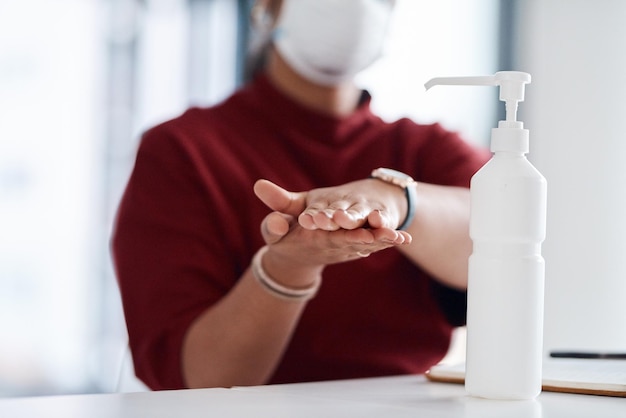 Foto richtige handhygiene kann die ausbreitung von keimen reduzieren nahaufnahme einer nicht erkennbaren geschäftsfrau, die in einem büro händedesinfektionsmittel verwendet