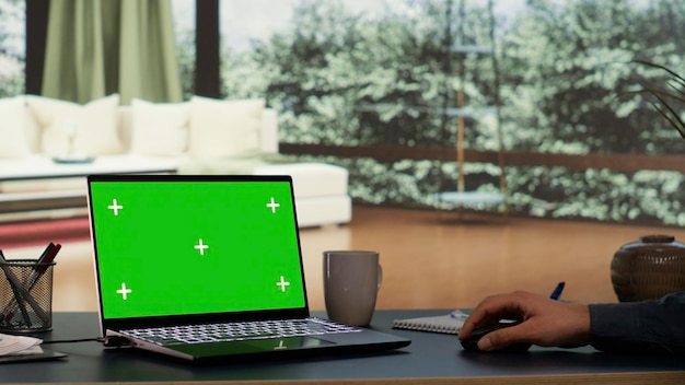 El rico empresario descansa en su excepcional villa alpina viendo la proyección de pantalla verde en su portátil El director internacional interactúa en la computadora con una pantalla chromakey en blanco La vida cotidiana de lujo