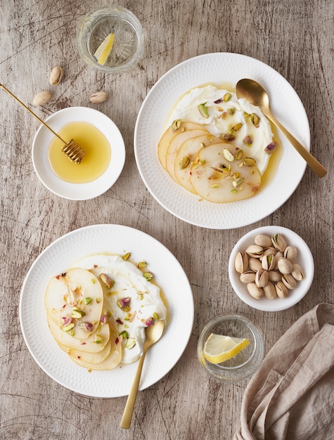 Ricotta con peras, pistachos y miel o jarabe de arce en dos placa blanca