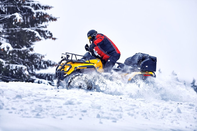 Rider conduciendo en la carrera de quad en invierno en el bosque