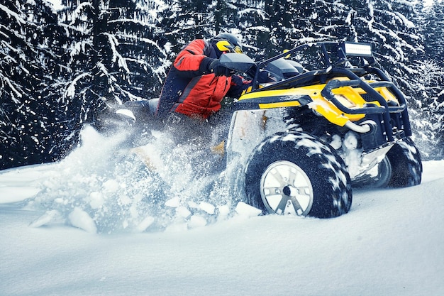 Rider conduciendo en la carrera de quad en invierno en el bosque