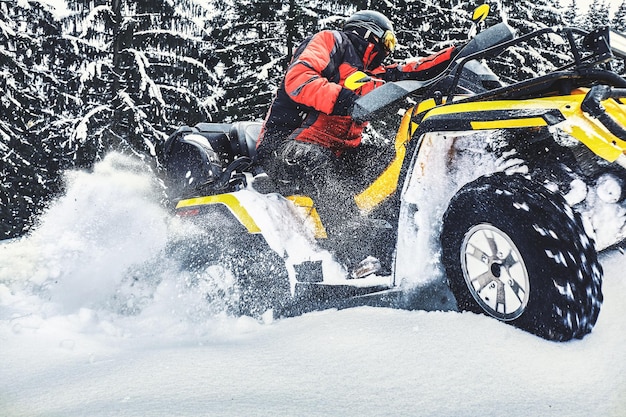 Rider conduciendo en la carrera de quad en invierno en el bosque