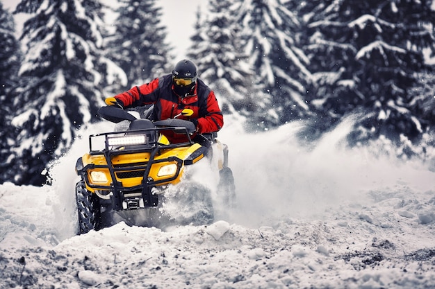 Rider conduciendo en la carrera de quad en invierno en el bosque