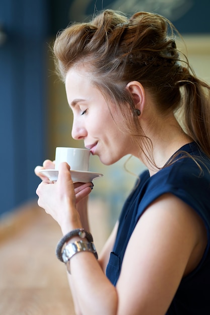 Foto riechendes aroma des weißen mädchens der rothaarigen des kaffees beim sitzen im café