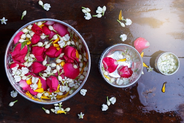 Riegue en el cazo del agua con el pedestal colorido de las flores para el festival de Songkran, Tailandia