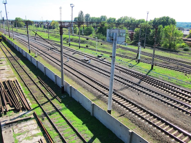 Rieles de ferrocarril colocados uniformemente cruzando el marco en diagonal Plataformas de observación de vías de ferrocarril Rieles para reparaciones detrás de la cerca Cables junto a zonas verdes Interruptores de transferencia Semáforos y mecanismos