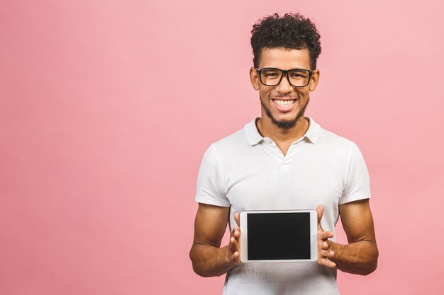 Riendo joven afroamericano macho sosteniendo un Touch Pad Tablet PC aislado sobre fondo rosa