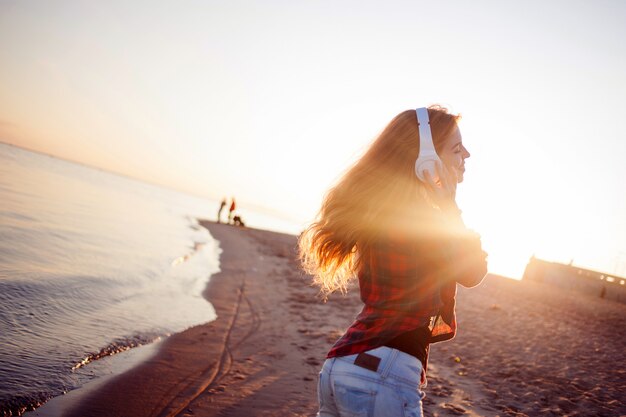 Riendo a joven disfrutando de la música. Retrato en la brillante luz del atardecer