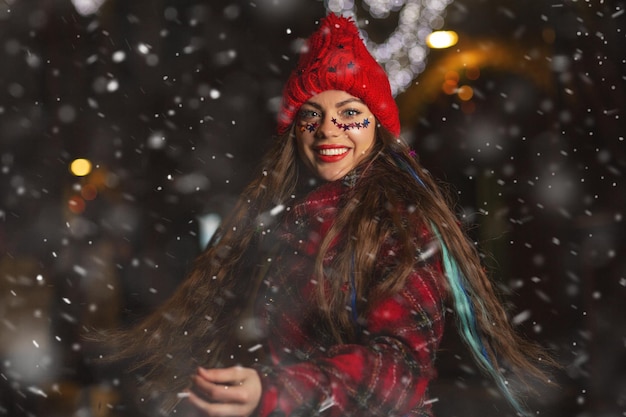 Riendo joven mujer de pelo largo disfrutando de la nieve en la feria de Navidad