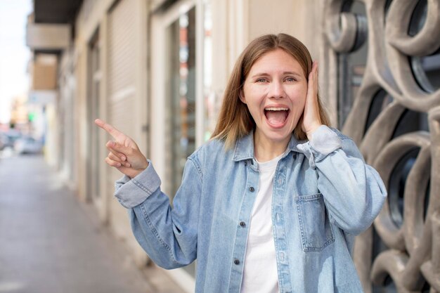 Riendo, luciendo feliz, positivo y sorprendido al darse cuenta de una gran idea que apunta al espacio de copia lateral