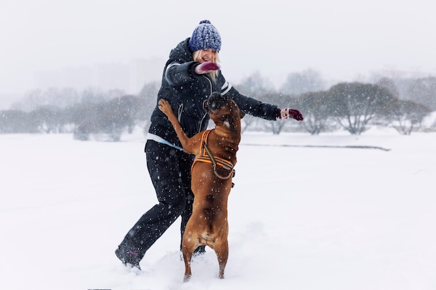 Riendo mujer juega con perro boxer en Winter Park. Amor y amistad.