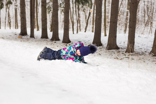 Riendo niña acostada en la nieve profunda.