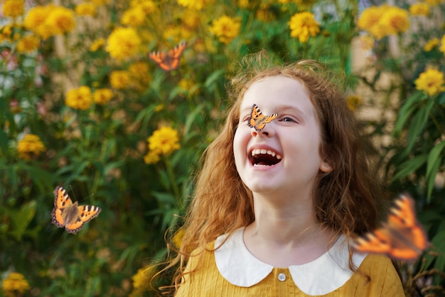 Riendo niña rizada con una mariposa en la nariz.