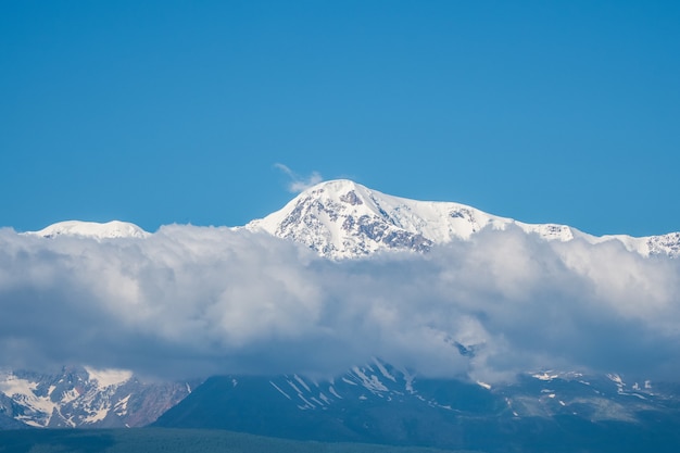 Riesengebirge mit Schnee über weißen Wolken am sonnigen Tag. Gletscher unter blauem Himmel. Erstaunliche verschneite Berglandschaft von majestätischer Natur.