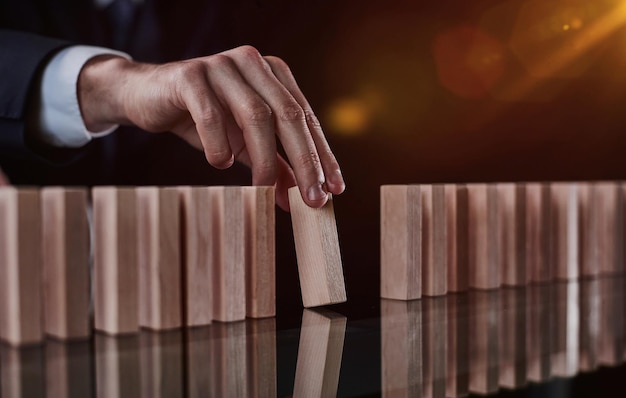 Riesgo de crear un concepto de crecimiento empresarial con bloques de madera La mano del hombre ha amontonado y apilado un bloque de madera